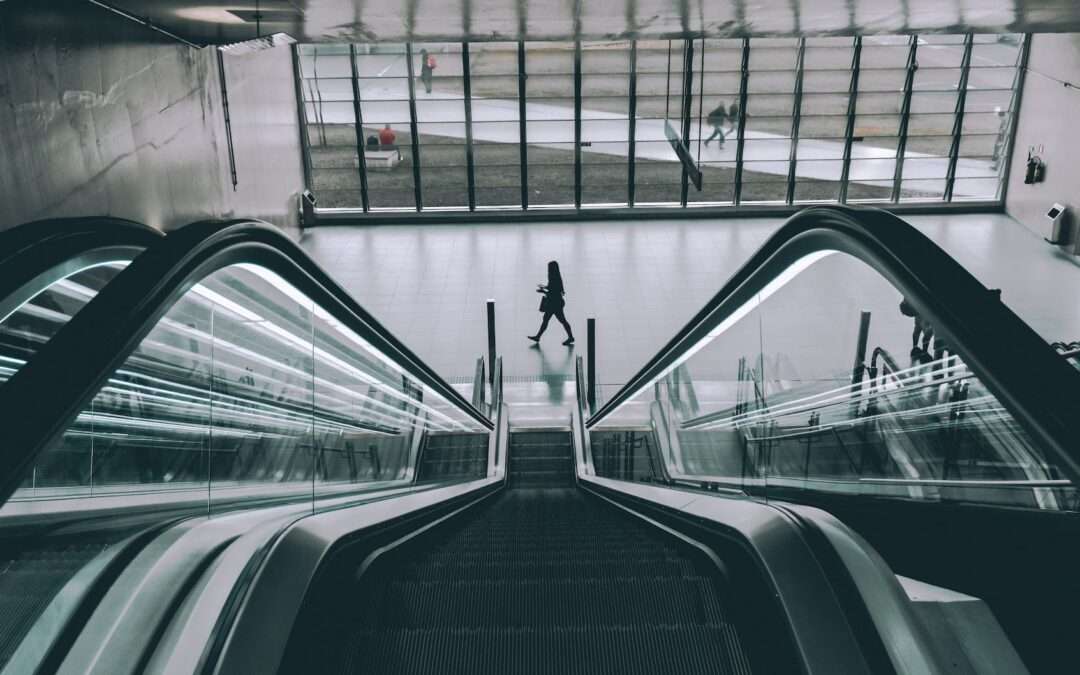grayscale photography of person walking near escalator