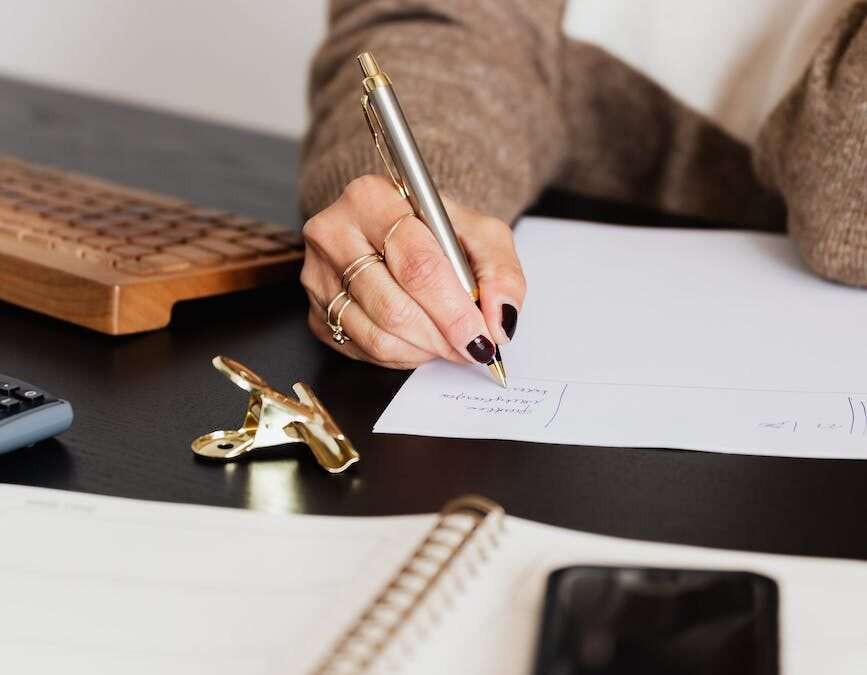 crop elegant business lady taking notes while sitting at desk